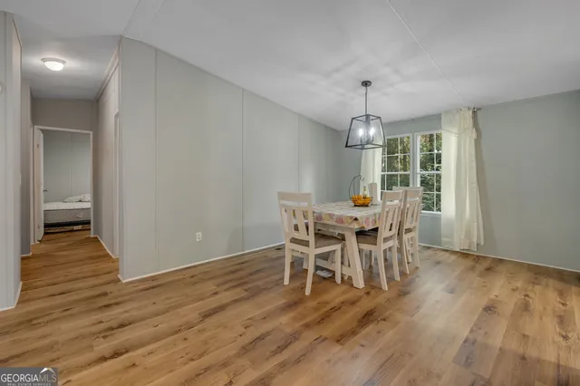 a dining room with wooden floor a chandelier a wooden table and chairs