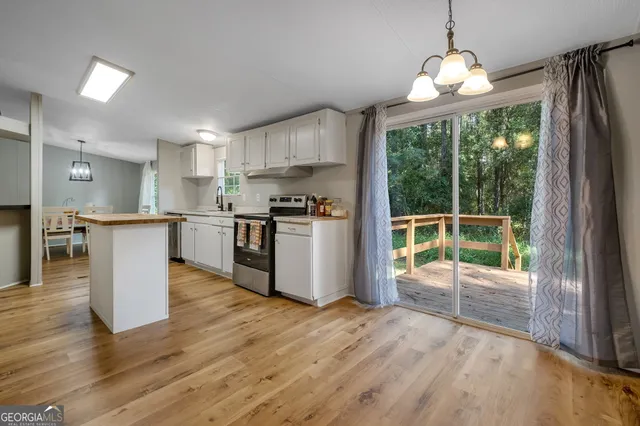 a kitchen with stainless steel appliances granite countertop a refrigerator a stove top oven and a large window with wooden floor