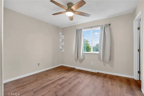 a view of empty room with wooden floor and fan