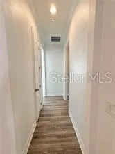 a view of a hallway with wooden floor and a bathroom