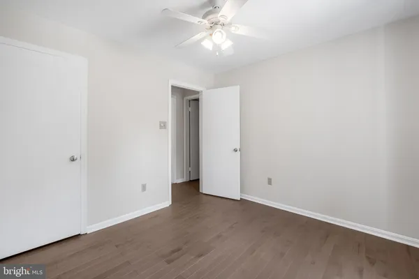 an empty room with wooden floor and fan