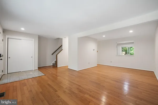an empty room with wooden floor and a ceiling fan