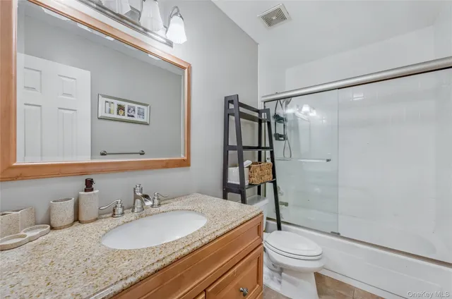 a bathroom with a granite countertop sink toilet mirror and shower