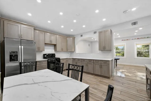 a kitchen with stainless steel appliances kitchen island granite countertop a stove a sink a refrigerator with a dining table and chairs