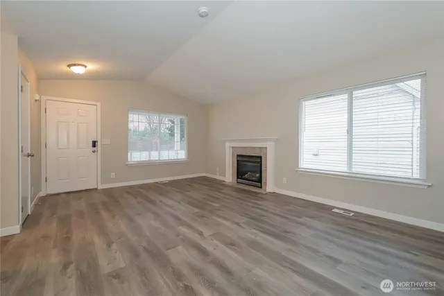 an empty room with windows and fireplace