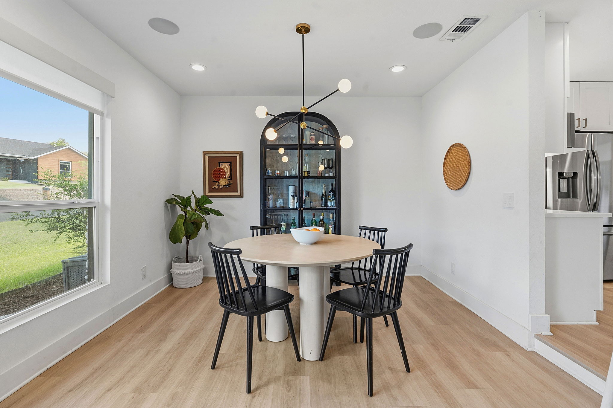4403 Elmsgrove Drive Austin, TX 78721 - Photo 9 of 38 A refined dining space features a sleek black hutch and a modern chandelier illuminating a circular table.