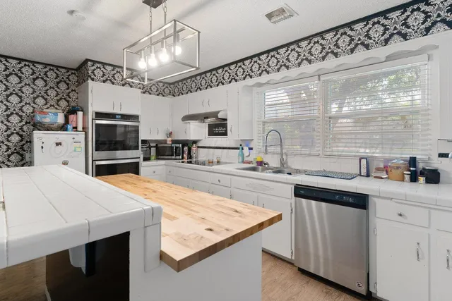 a kitchen with stainless steel appliances kitchen island granite countertop a sink a stove and a refrigerator