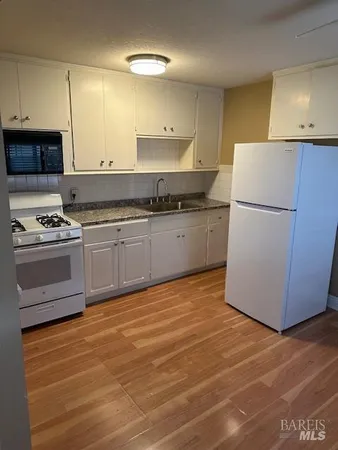 a kitchen with granite countertop a stove a sink and a refrigerator