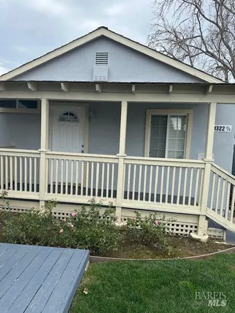 a view of a house with a small yard and wooden floor and fence