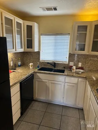 a white kitchen with granite countertop a sink and dishwasher a stove top oven with granite countertops