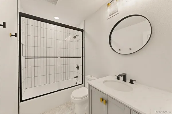 a bathroom with a granite countertop sink mirror vanity and toilet