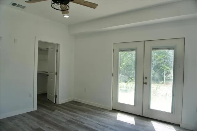 a view of an empty room with window and wooden floor