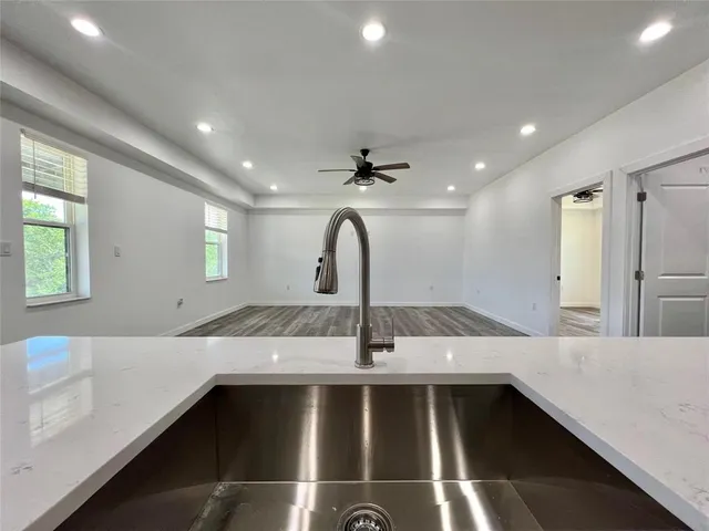 a large kitchen with a large counter top a sink and stainless steel appliances