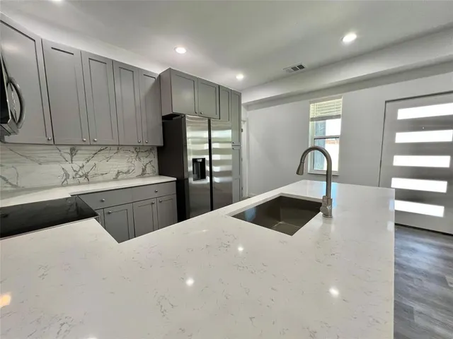 a kitchen with a sink a refrigerator and cabinets