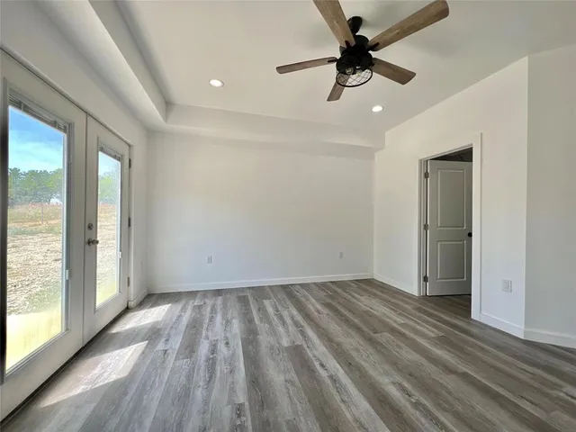 a view of empty room with wooden floor and fan