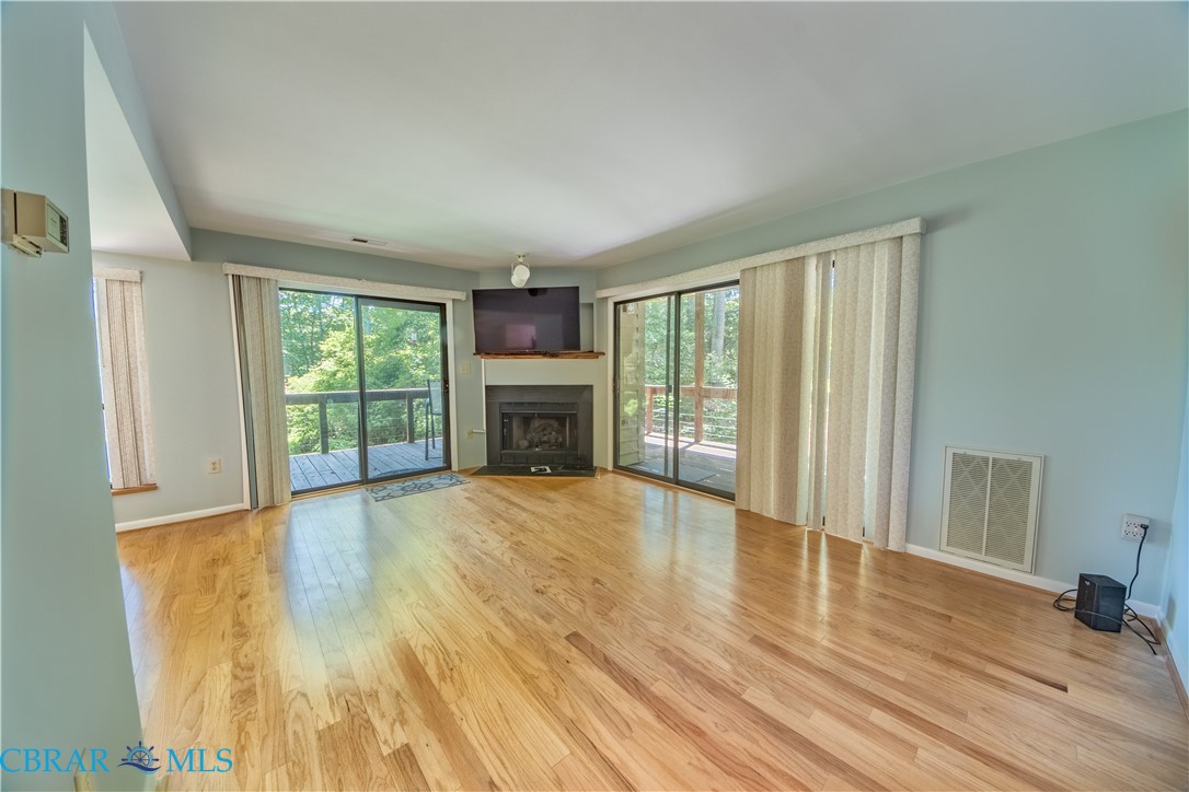 54 Villa Ridge Drive, Unit C Hartfield, VA 23071 - Photo 22 of 45 Unfurnished living room featuring light wood-style flooring and a fireplace with flush hearth