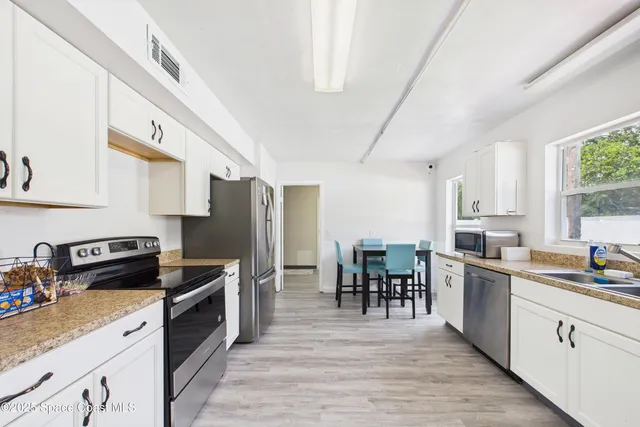 a kitchen with granite countertop a sink cabinets and stainless steel appliances