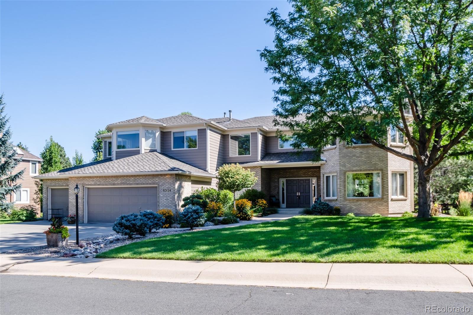 a front view of a house with a garden and trees