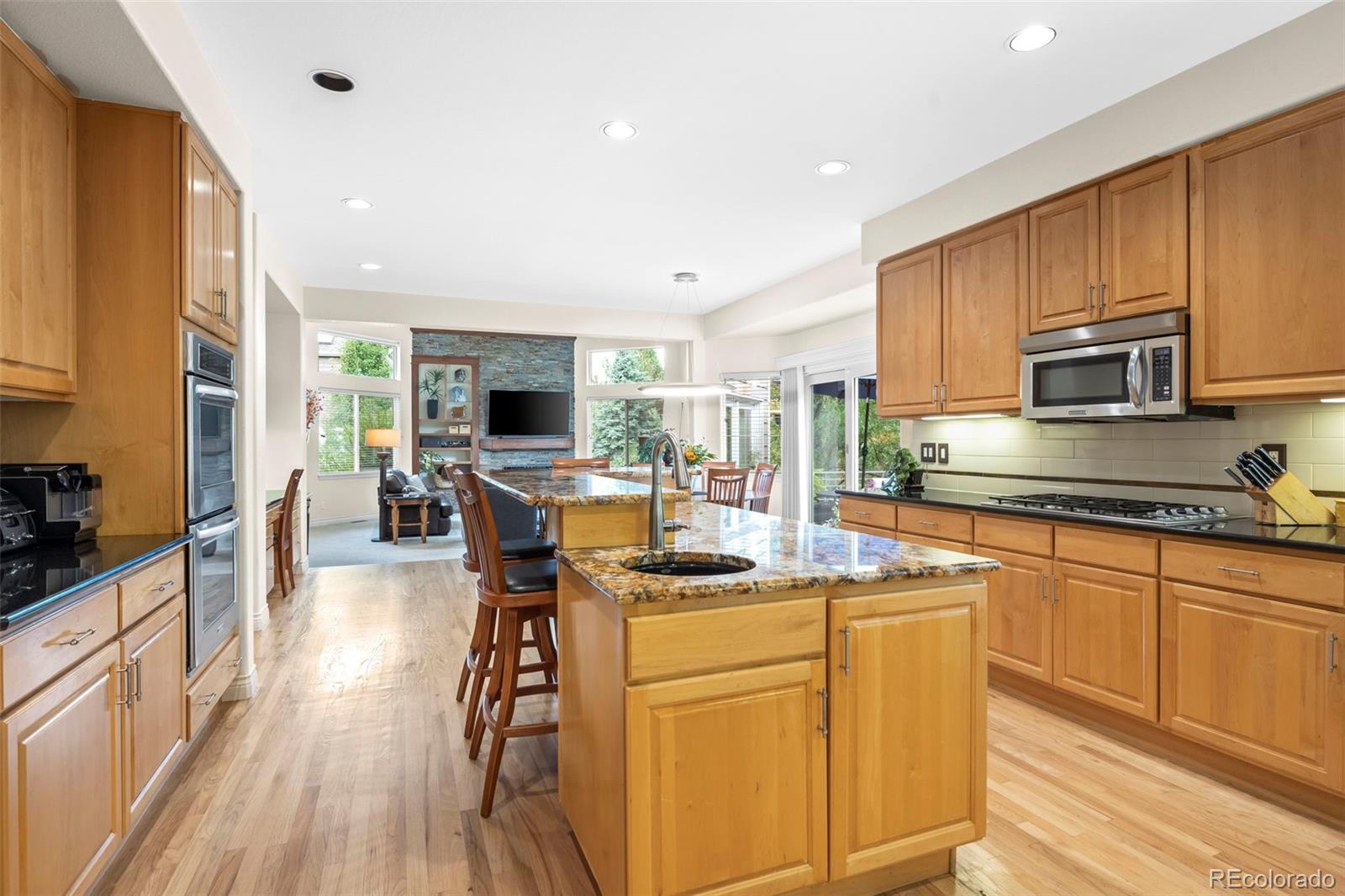 5236 Pinehurst Drive Boulder, CO 80301 - Photo 7 of 40 a kitchen with stainless steel appliances kitchen island granite countertop a stove top oven a sink dishwasher a dining table and chairs with wooden floor