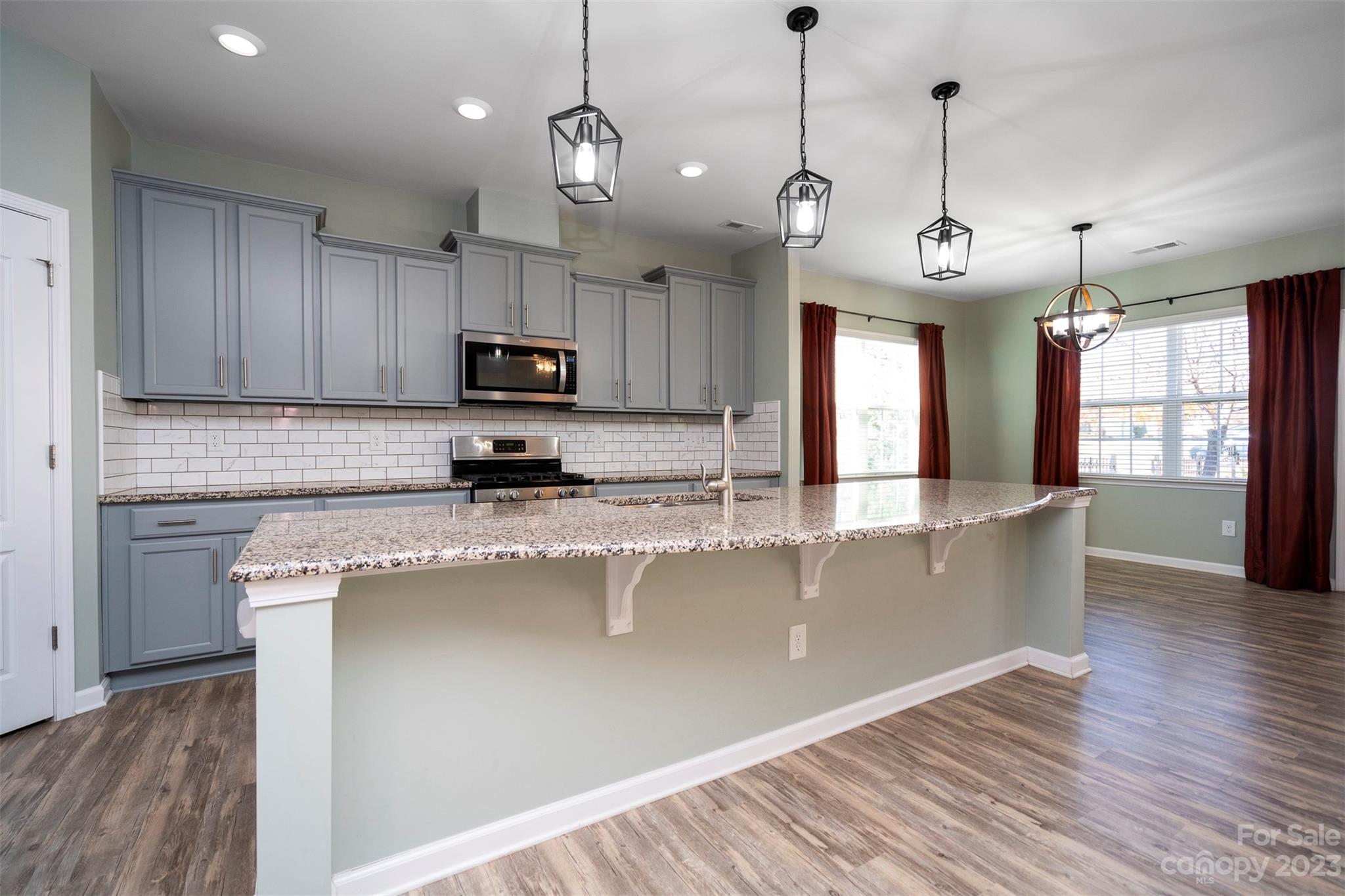 8202 Asher Chase Trail Lancaster, SC 29720 - Photo 16 of 42 a large kitchen with granite countertop a stove a sink a refrigerator and a wooden floor