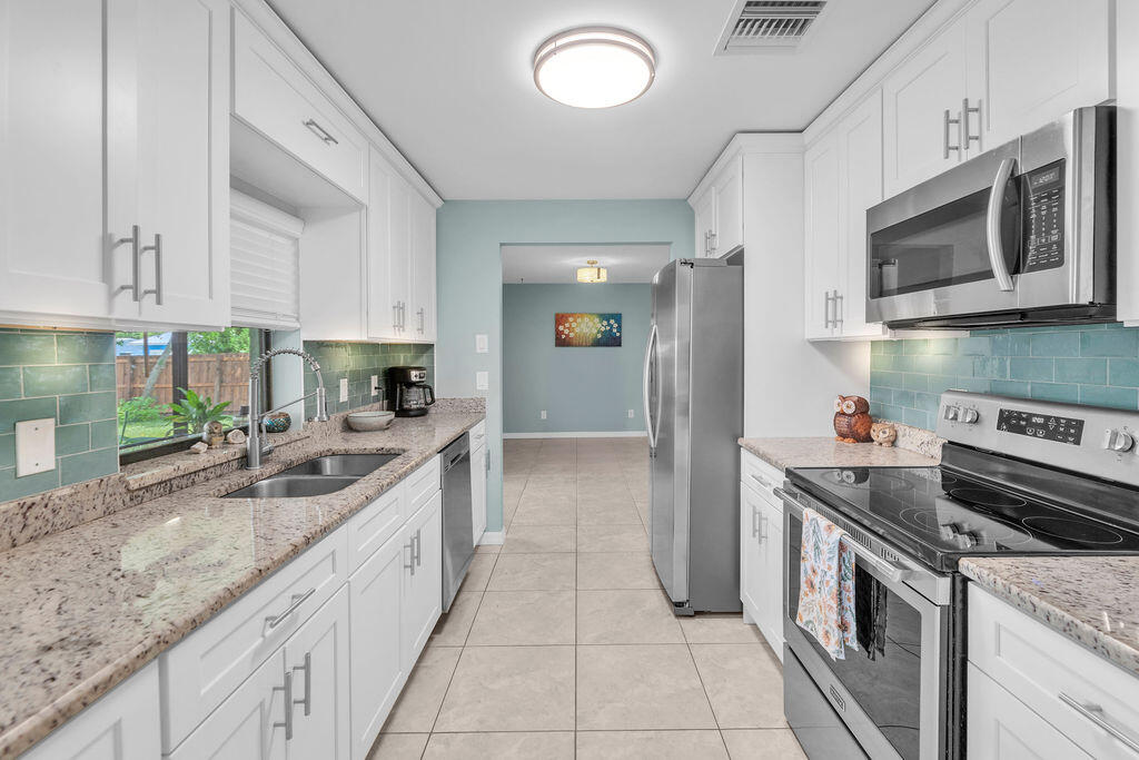 2402 Southeast Pinero Road Port St. Lucie, FL 34952 - Photo 33 of 45 a kitchen with stainless steel appliances granite countertop a sink and a stove
