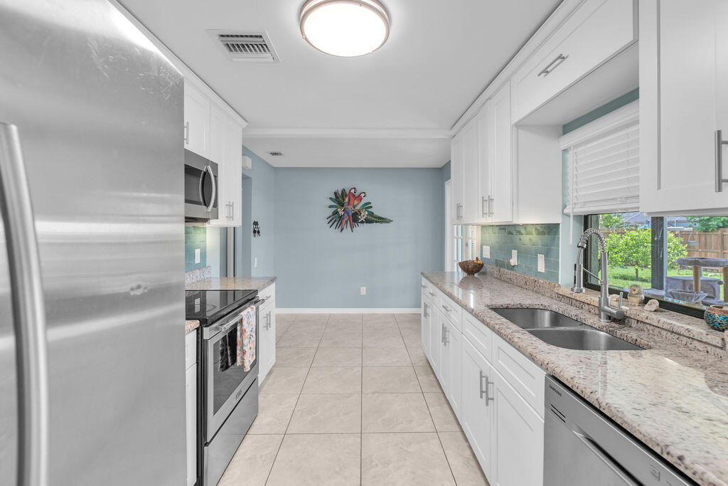 2402 Southeast Pinero Road Port St. Lucie, FL 34952 - Photo 35 of 45 a kitchen with granite countertop a sink and a stove