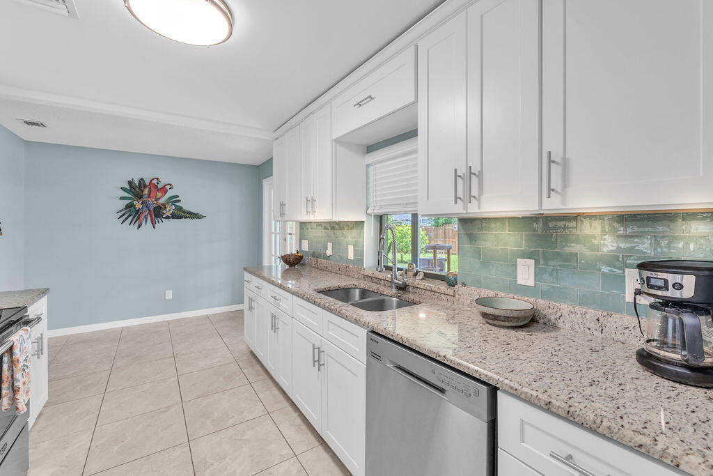 2402 Southeast Pinero Road Port St. Lucie, FL 34952 - Photo 36 of 45 a kitchen with granite countertop a sink a stove and cabinets