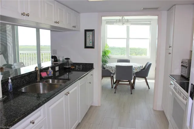 a kitchen with granite countertop a sink and white cabinets with wooden floor