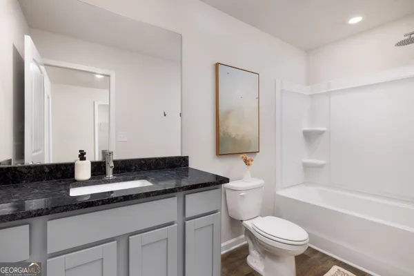 a bathroom with a granite countertop sink a toilet and shower