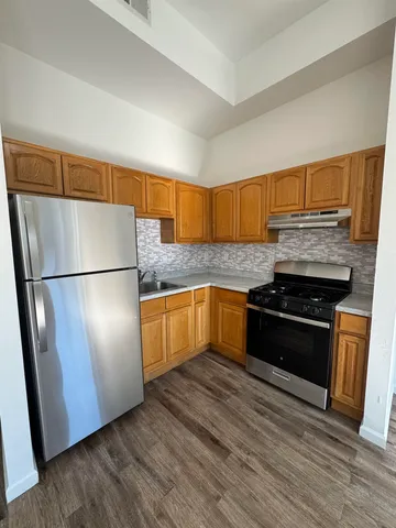 a kitchen with granite countertop wooden floors stainless steel appliances and a counter space