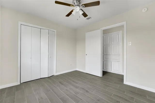 a view of empty room with wooden floor and fan