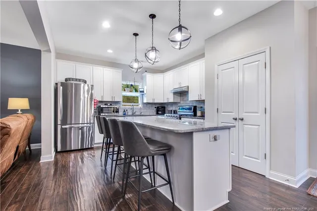 a kitchen with stainless steel appliances a refrigerator a sink dishwasher a stove and white countertops with wooden floor