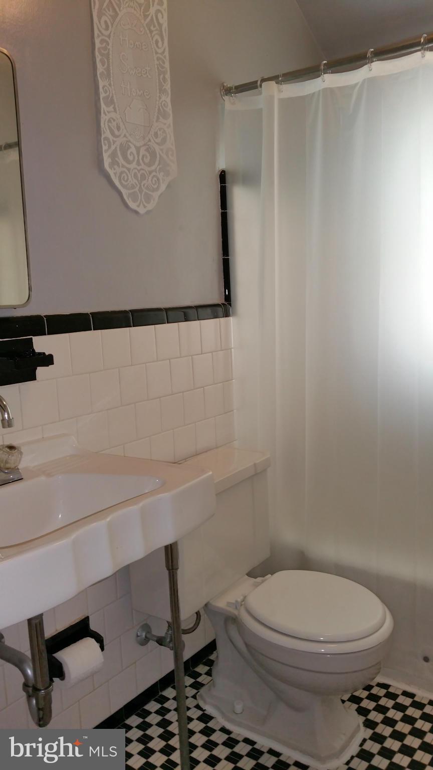 3902 Colchester Road Baltimore, MD 21229 - Photo 13 of 27 a bathroom with a toilet and a shower curtain
