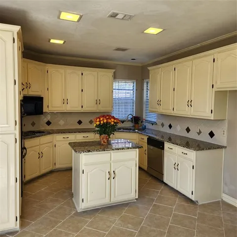 a kitchen with granite countertop white cabinets sink and stainless steel appliances