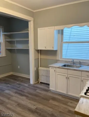 a kitchen with granite countertop a sink cabinets and a wooden floor