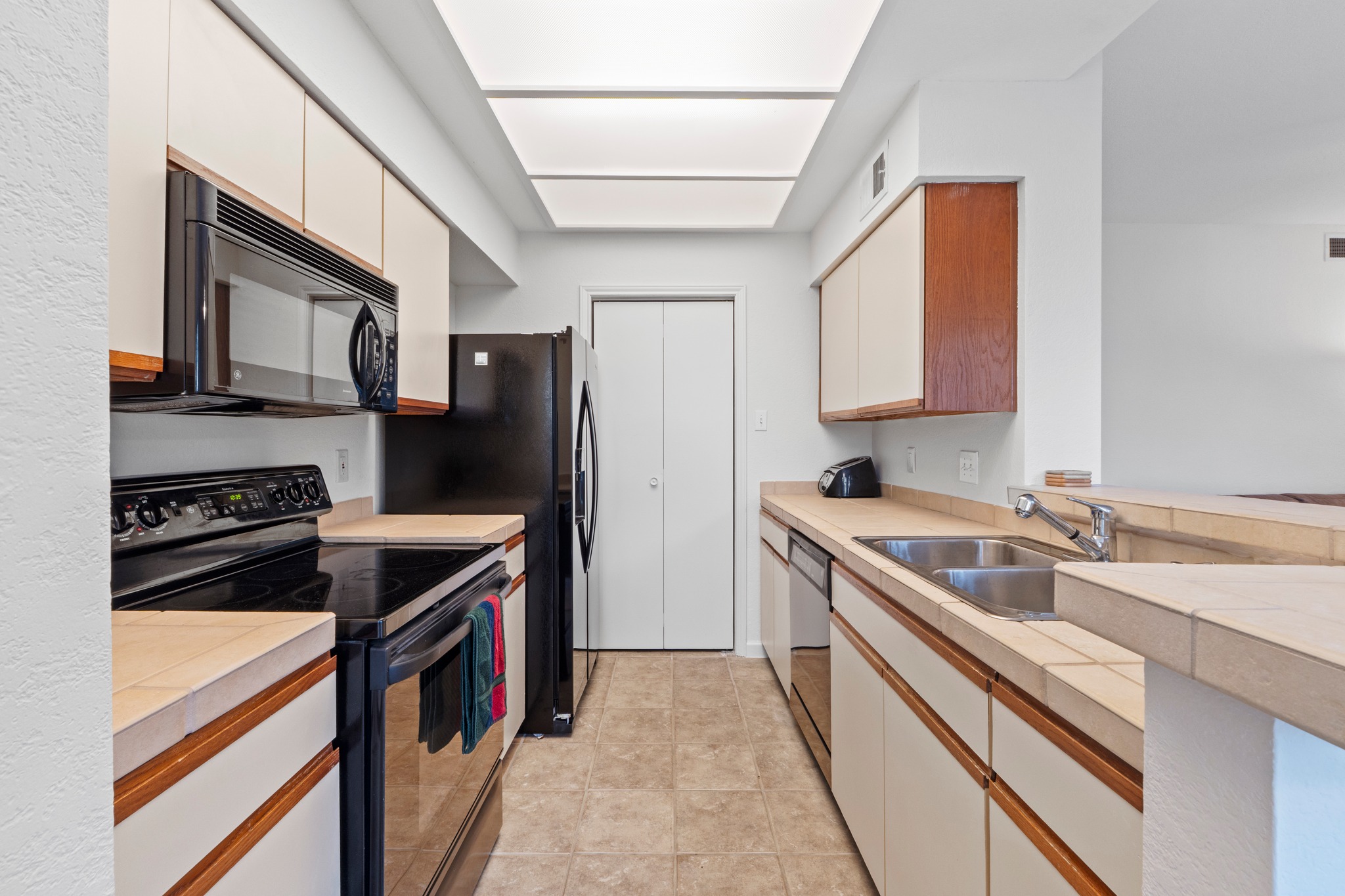 4711 Spicewood Springs Road, Unit 8146 Austin, TX 78759 - Photo 10 of 17 Galley kitchen featuring a black electric range, over-the-range microwave, and matching refrigerator