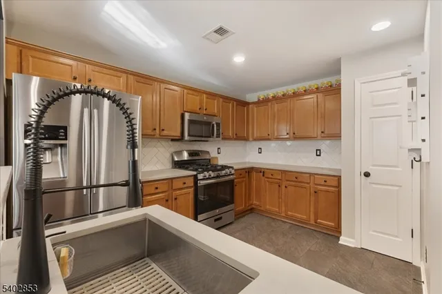 a kitchen with stainless steel appliances granite countertop a refrigerator oven a sink dishwasher and white cabinets with wooden floor