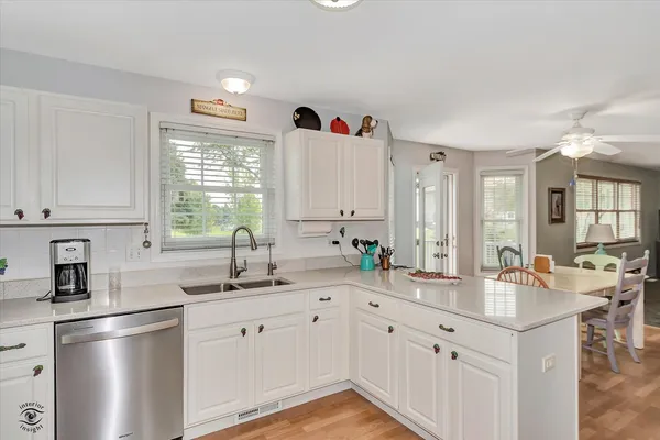 a kitchen with a sink dishwasher a stove and white cabinets with wooden floor