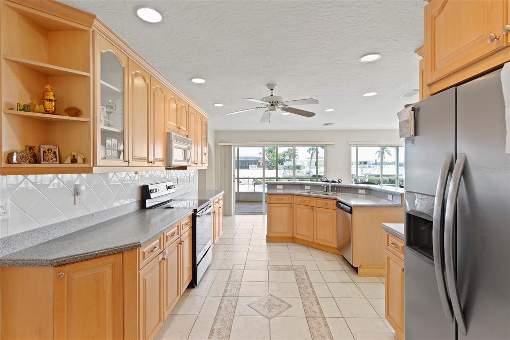 4964 South Shore Drive New Port Richey, FL 34652 - Photo 11 of 69 a large kitchen with stainless steel appliances granite countertop a refrigerator a sink dishwasher a stove and white countertops with wooden floor