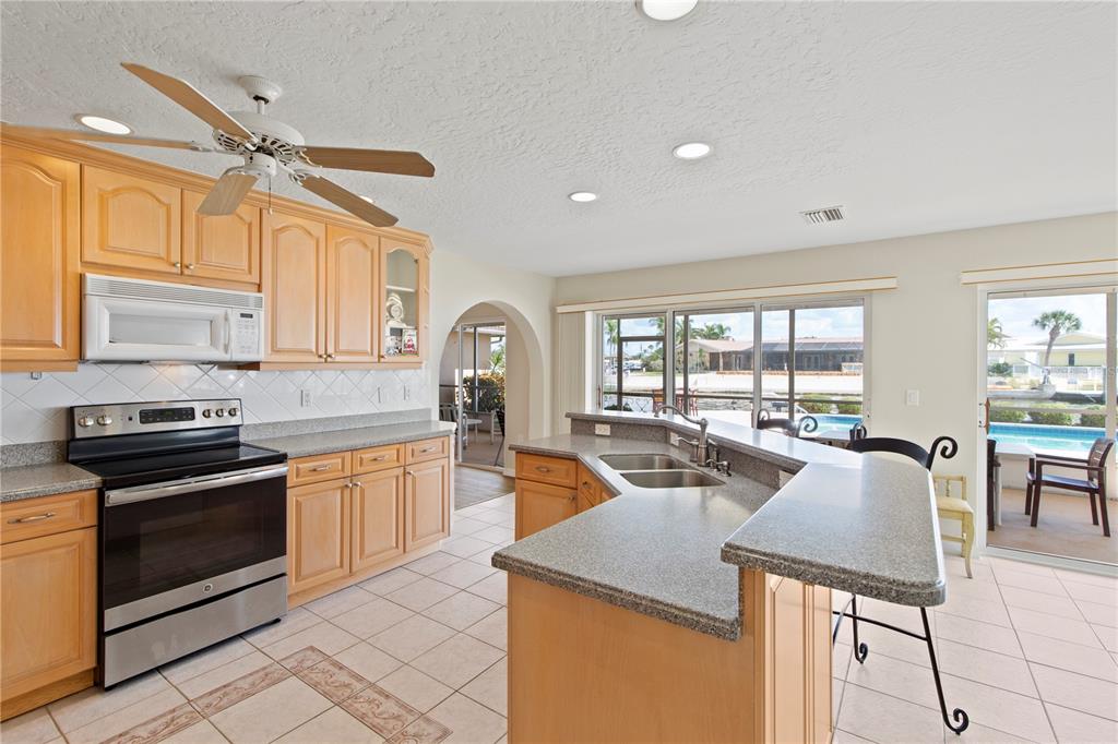 4964 South Shore Drive New Port Richey, FL 34652 - Photo 15 of 69 a open kitchen with granite countertop a stove top oven a sink a dining table and chairs with wooden floor
