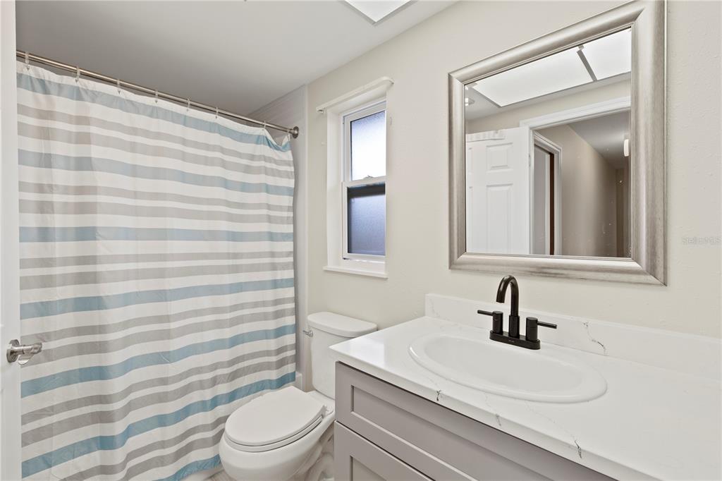 4964 South Shore Drive New Port Richey, FL 34652 - Photo 38 of 69 a bathroom with a sink a toilet a mirror and shower curtain