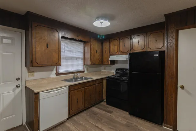 a kitchen that has a sink stainless steel appliances a refrigerator and cabinets