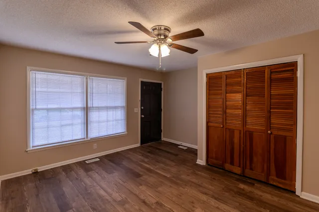 an empty room with wooden floor closet and windows