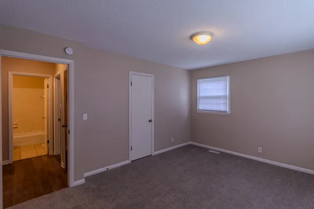 a view of an empty room with closet and a window
