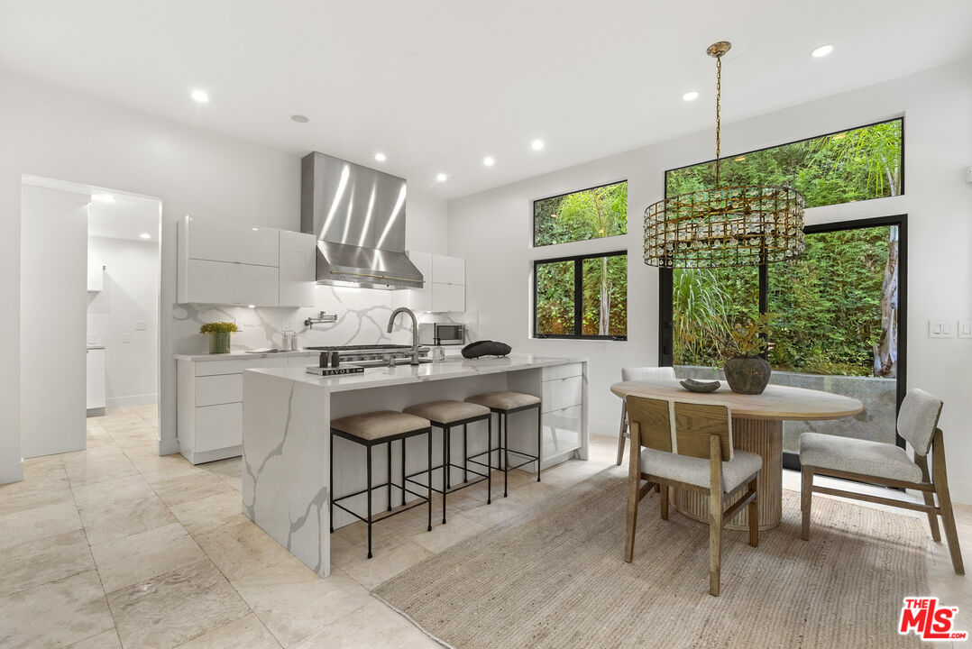 9782 Oak Pass Road Beverly Hills, CA 90210 - Photo 10 of 27 a kitchen with kitchen island a dining table chairs and white cabinets