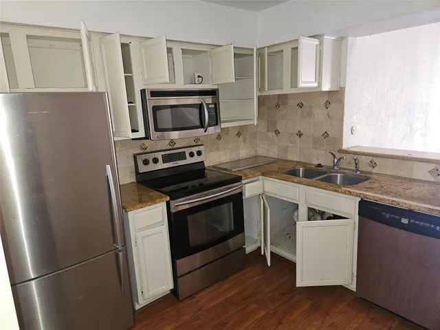 a kitchen with granite countertop a sink cabinets and wooden floor