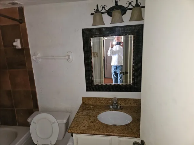 a bathroom with a granite countertop toilet sink and mirror