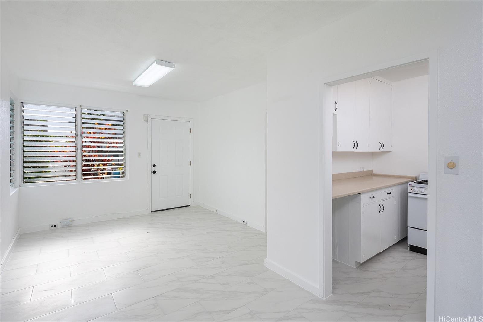 a view of a kitchen with white cabinets and a window