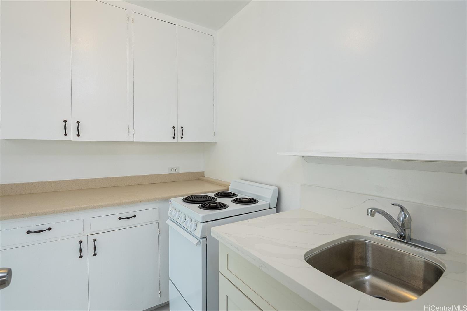1115 Hassinger Street, Unit C Honolulu, HI 96822 - Photo 2 of 11 a kitchen with sink cabinets and a stove with wooden floor