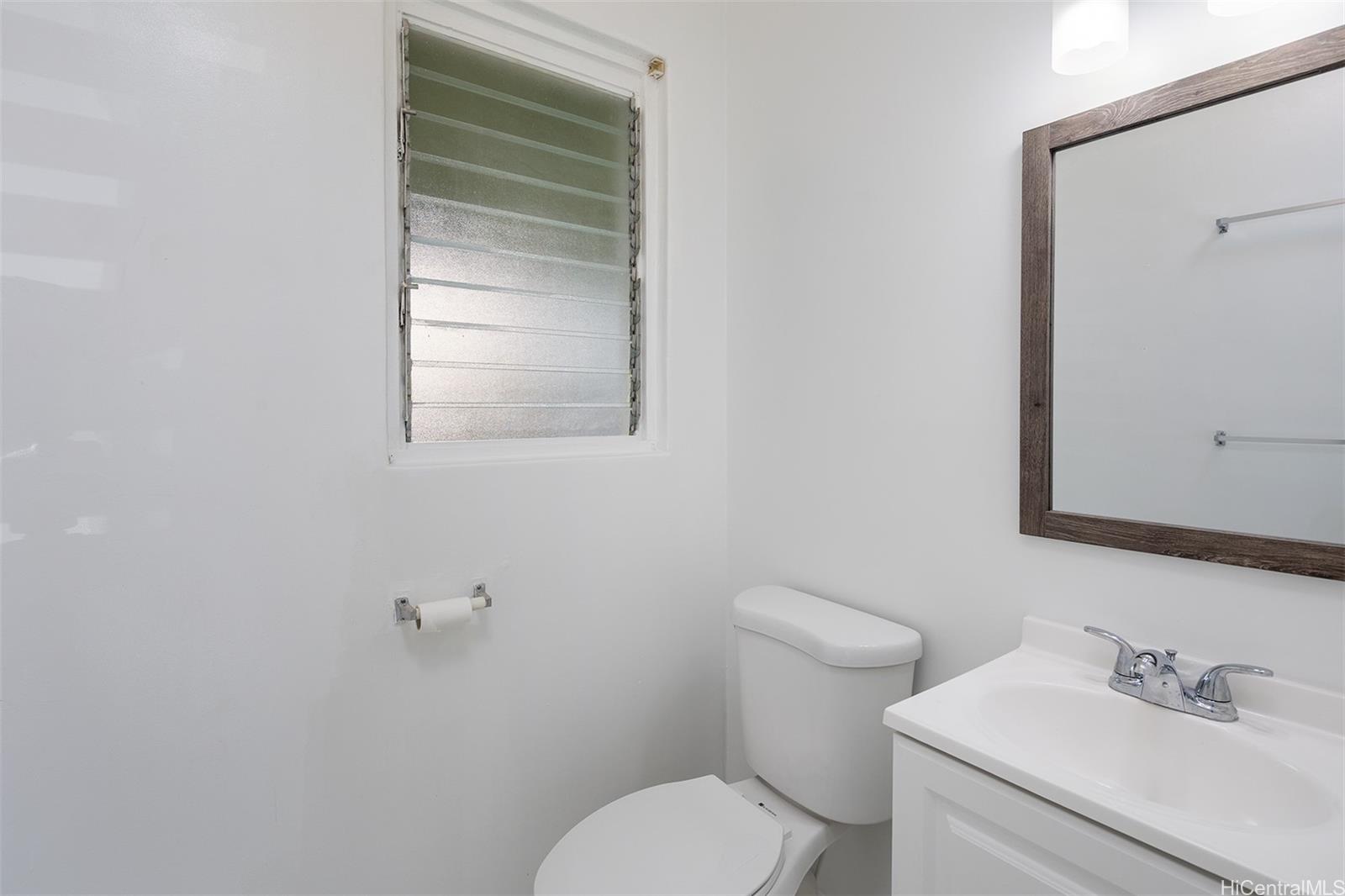 1115 Hassinger Street, Unit C Honolulu, HI 96822 - Photo 10 of 11 a bathroom with a toilet sink and mirror